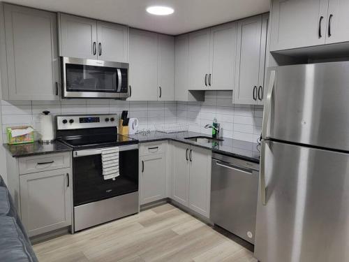 eine Küche mit weißen Schränken und einem Kühlschrank aus Edelstahl in der Unterkunft Serene Haven - 1 bedroom apartment. in Calgary