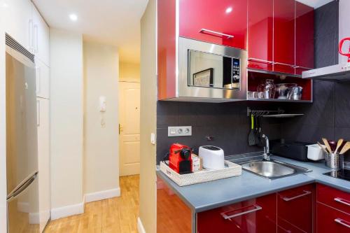 een keuken met rode kasten en een wastafel bij Perfect one bedroom apartment in Madrid