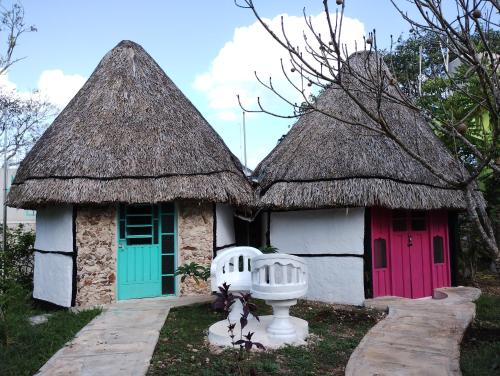a small cottage with a thatched roof and a red door at Hotel y Museo Aldea Maya Toktli Orígenes - Suite Casa Maya 3 Culturas - Alberca, Wifi Starlink, Tour Museo in Izamal