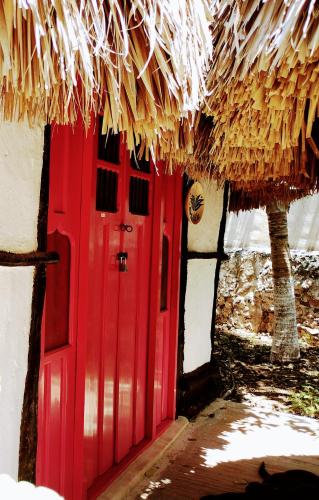 a red door of a house with a straw roof at Hotel y Museo Aldea Maya Toktli Orígenes - Suite Casa Maya 3 Culturas - Alberca, Wifi Starlink, Tour Museo in Izamal