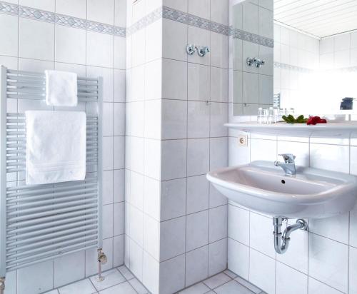 a white bathroom with a sink and a mirror at Hotel Landsknecht in Uckerath