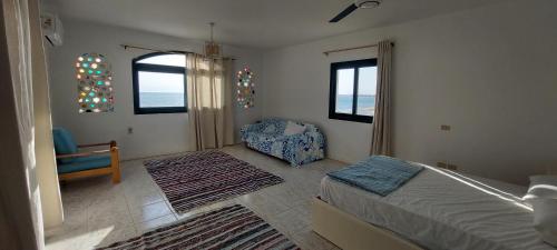 a bedroom with a bed and a chair and windows at Sea Pearl in Ras Sedr