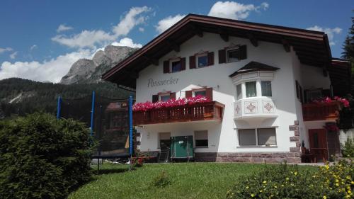 a white house with a balcony with pink flowers at Apartment Pössnecker in Selva di Val Gardena