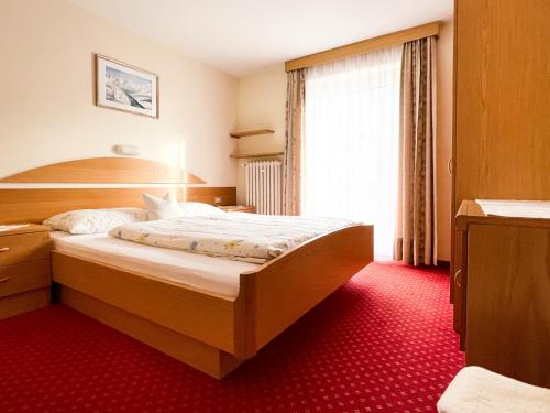 a hotel room with a bed with a red carpet at Apartment Pössnecker in Selva di Val Gardena