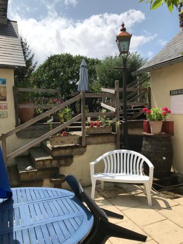 a patio with a bench and a table and an umbrella at Cottage Les Glycines in Javron-Les-Chapelles