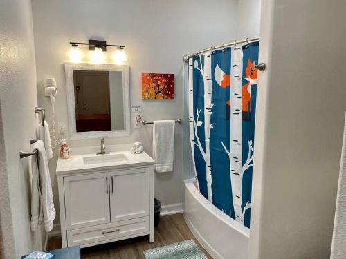 a bathroom with a sink and a shower curtain at Foxs Den Hot Tub Bbq Queen Bed Sleeps 2 in Ahwahnee