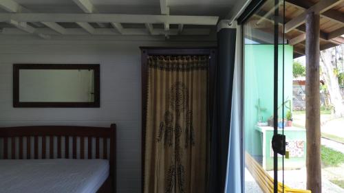 sypialnia z łóżkiem i oknem z zasłoną w obiekcie Morada Alto Astral w mieście Imbituba