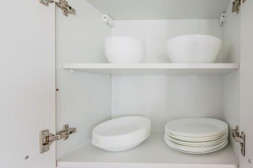 a white kitchen with plates and bowls on shelves at T&K Apartments - Bergisch Gladbach - 3 Comfortable Apartments - 18 min to Fair Messe Cologne in Bergisch Gladbach