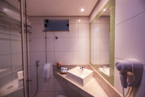 a bathroom with a sink and a mirror and a shower at Opaba Praia Hotel in Ilhéus