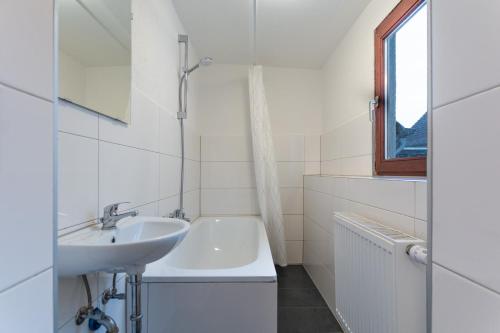 a white bathroom with a sink and a bath tub at T&K Apartments - Duisburg - 3 and 4 Room Monteur Apartments in Duisburg
