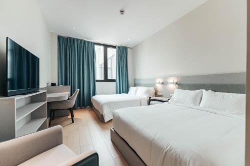 a hotel room with two beds and a flat screen tv at Elements Hotel & Shops Curaçao in Willemstad