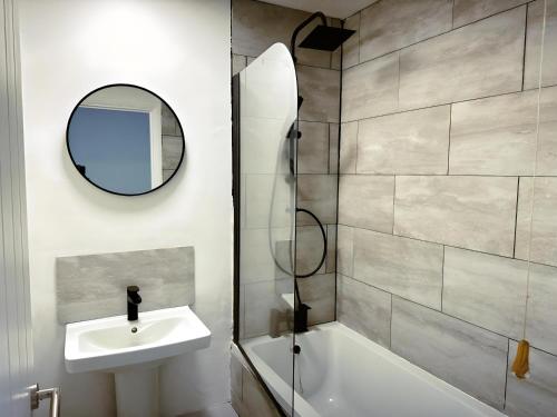 uma casa de banho com um lavatório, uma banheira e um espelho. em New Stylish 2 Bedroom House em Kent