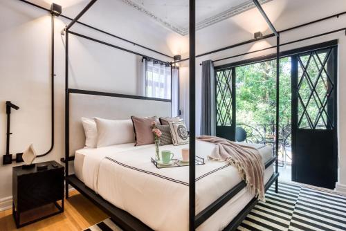 1 dormitorio con cama con dosel y ventana en UTOPIC Campos Elíseos by ULIV, en Ciudad de México