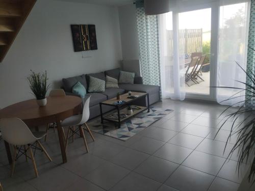 a living room with a couch and a table at charmante maison au calme avec jardin, terrasse et jacuzzi in Barjouville