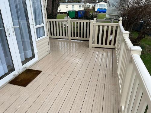 a wooden deck with a white railing and a house at Memories Made in Selsey
