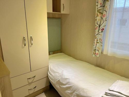 a small bedroom with a bed and a cabinet at Memories Made in Selsey