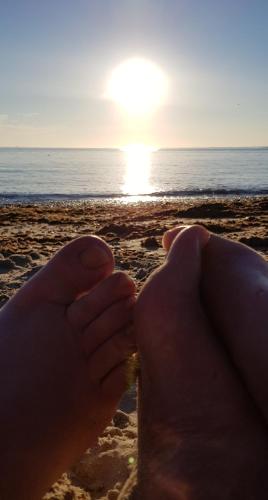 a person holding a glass of beer on the beach at Memories Made in Selsey