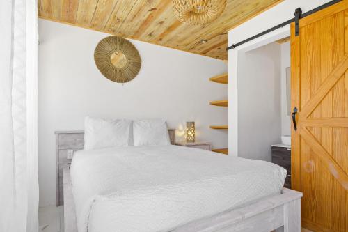 um quarto com uma cama branca e um tecto de madeira em Esmeralda 126 em Palm Beach