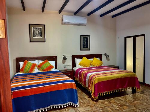 dos camas sentadas una al lado de la otra en un dormitorio en Hotel casa teresa café galería, en Juchitán de Zaragoza