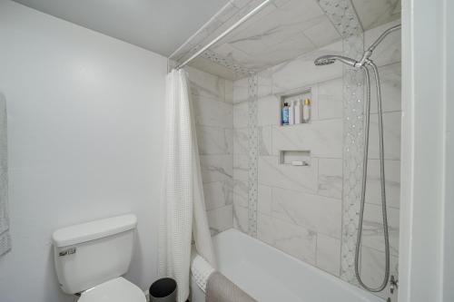 a white bathroom with a shower and a toilet at Downtown Tulsa Apartment - Near BOK Center! in Tulsa