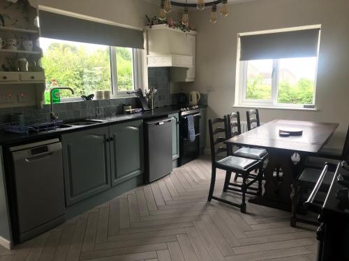 eine Küche mit einem Tisch und einem Waschbecken sowie einem Tisch und Stühlen in der Unterkunft Eden Cottage in Lisburn
