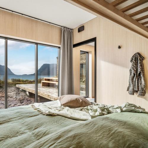 ein Schlafzimmer mit einem großen Bett und einem großen Fenster in der Unterkunft NEW! Luxury Cabin in beautiful Lofoten in Kleppstad