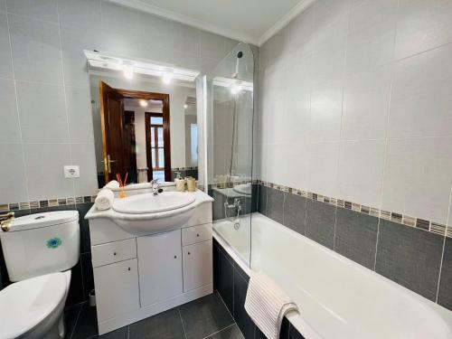 ein Badezimmer mit einem Waschbecken, einer Badewanne und einem WC in der Unterkunft Excelente apartamento con garaje y piscina in Ramales de la Victoria