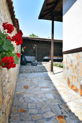 a stone walkway with a bench and red flowers at GERANA HOUSE in Kilifarevo
