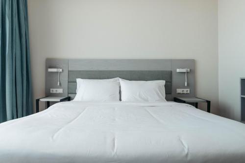 a large bed with white sheets and pillows at Elements Hotel & Shops Curaçao in Willemstad