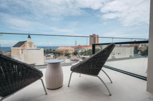 two chairs and a table on a balcony with a view at Elements Hotel & Shops Curaçao in Willemstad