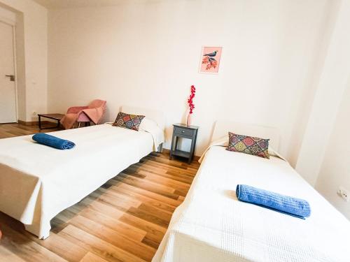 two white beds in a room with wooden floors at By La Boqueria Rooms in Barcelona