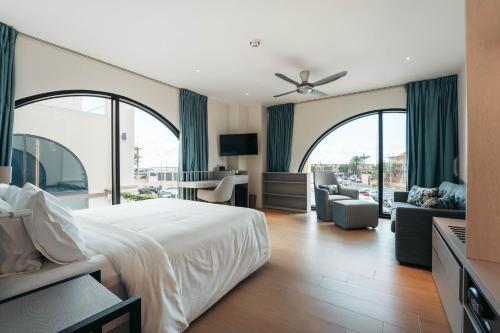 a bedroom with a large bed and a living room at Elements Hotel & Shops Curaçao in Willemstad