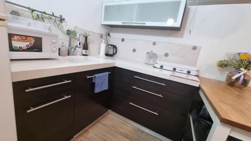 a kitchen with black cabinets and a sink and a microwave at Luxury peaceful, free parking in Rechovot