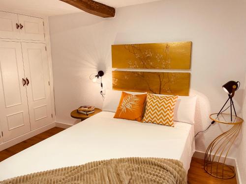 a bedroom with a white bed with orange pillows at Alojamiento Singular Casa Haraiz in Jaraiz de la Vera