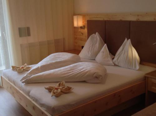 a bed with white sheets and flowers on it at Hotel Garni Savoy - new opening in Castelrotto