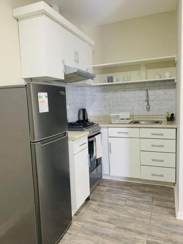 uma cozinha com um frigorífico de aço inoxidável e armários brancos em M’iski house em Urbanizacion Buenos Aires