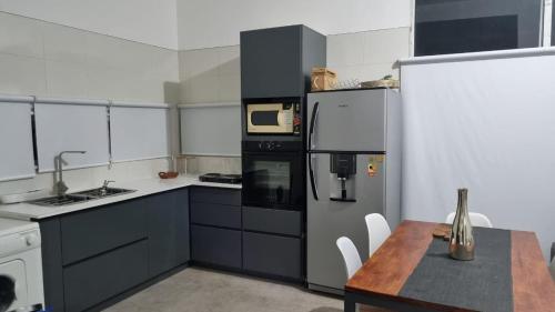 una cocina con electrodomésticos en blanco y negro y una mesa en Posada en Mendoza en El Challao