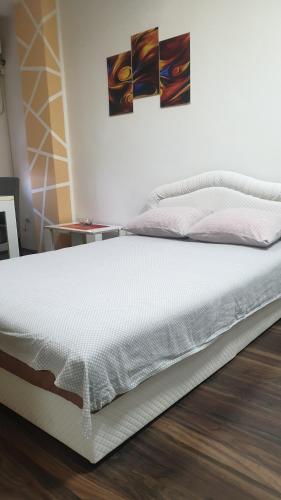 uma cama branca sentada num piso de madeira num quarto em Apartmani Borko 1-1 em Loznica