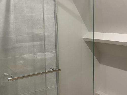 une douche avec une porte vitrée dans une salle de bain dans l'établissement Charmant Cottage 2P avec Jardin et WIFI, à 2 Pas de la Plage de Cabourg - FR-1-487-285, à Cabourg