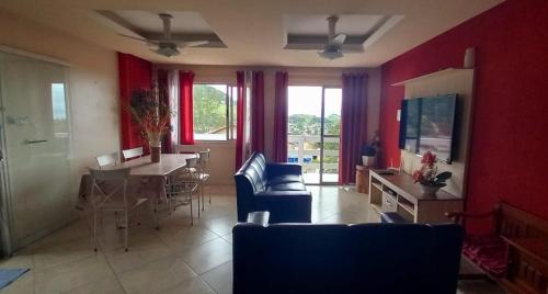 ein Wohnzimmer mit roten Wänden, einem Tisch und Stühlen in der Unterkunft Casa com Belas vistas - Muriqui in Mangaratiba