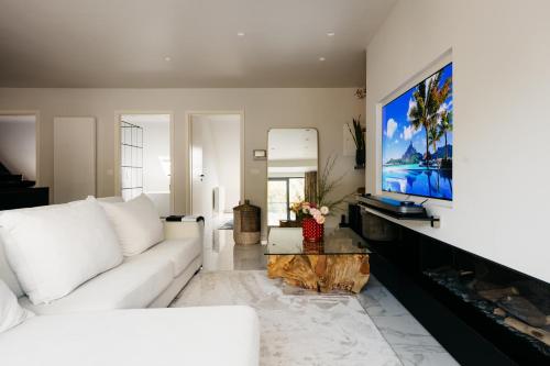 sala de estar con sofá blanco y TV de pantalla plana en The Edgewater Suites - RIVERSIDE en Namur