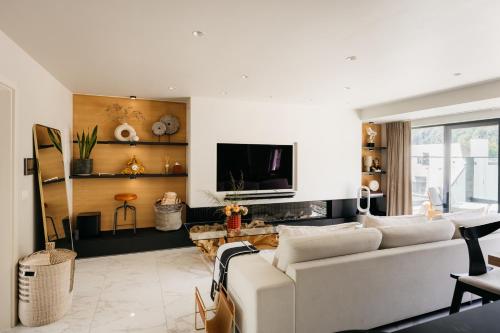 - un salon avec un canapé blanc et une télévision dans l'établissement The Edgewater Suites - RIVERSIDE, à Namur