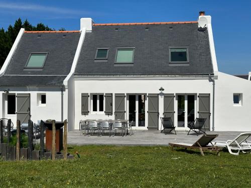 ein großes weißes Haus mit Stühlen und Tischen auf einer Terrasse in der Unterkunft Maison spacieuse à deux pas de la plage … in Le Palais