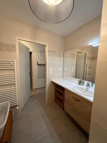 une salle de bain avec un lavabo et un grand miroir dans l'établissement Résidence de la Brasserie, à Saint-Valery-sur-Somme
