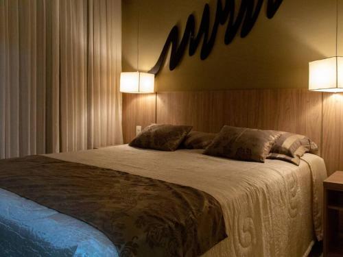 1 dormitorio con 1 cama grande con 2 luces. en Apartamento Quartier no Parque Aldeia das Aguas, en Barra do Piraí