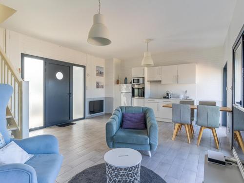 Il comprend un salon avec des chaises bleues et une cuisine. dans l'établissement Superbe T3 rénové à 200m de l'océan avec terrasse et parking privatif - FR-1-50-74, à Mimizan