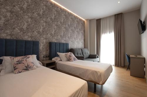 una camera d'albergo con due letti e un divano di Hotel Aldama a Mérida