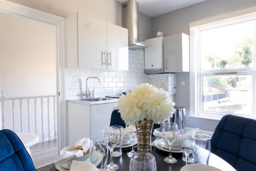 een keuken met een tafel met een vaas met bloemen erop bij 2 Bed Apartment by AV Stays Short Lets & Serviced Accommodation Sittingbourne Kent in Kent