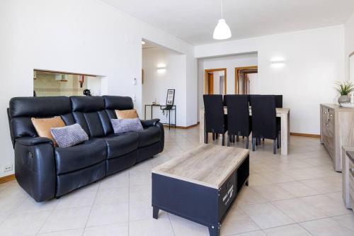 a living room with a black couch and a table at Sea-Front near Vilamoura - with AC, WiFi, Netflix in Quarteira