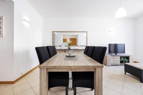 une salle à manger avec une table en bois et des chaises noires dans l'établissement Sea-Front near Vilamoura - with AC, WiFi, Netflix, à Quarteira